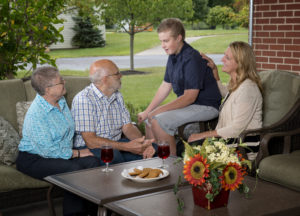 Two retired seniors relaxing outside with their family
